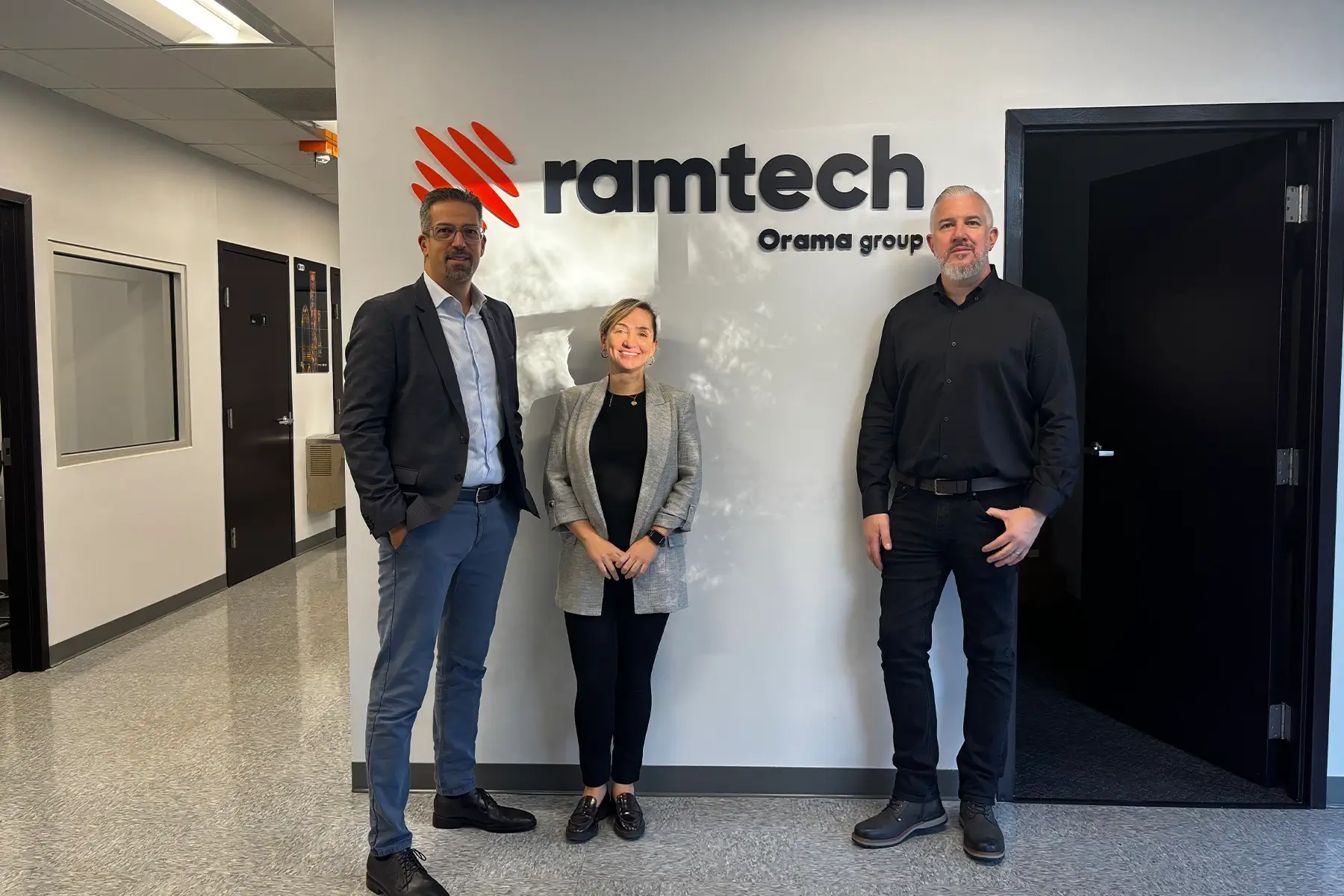 Ramtech Charlotte office opening ceremony with Bruna Esposito, James Pecz, and Giorgio Koursaris standing by the Ramtech logo.