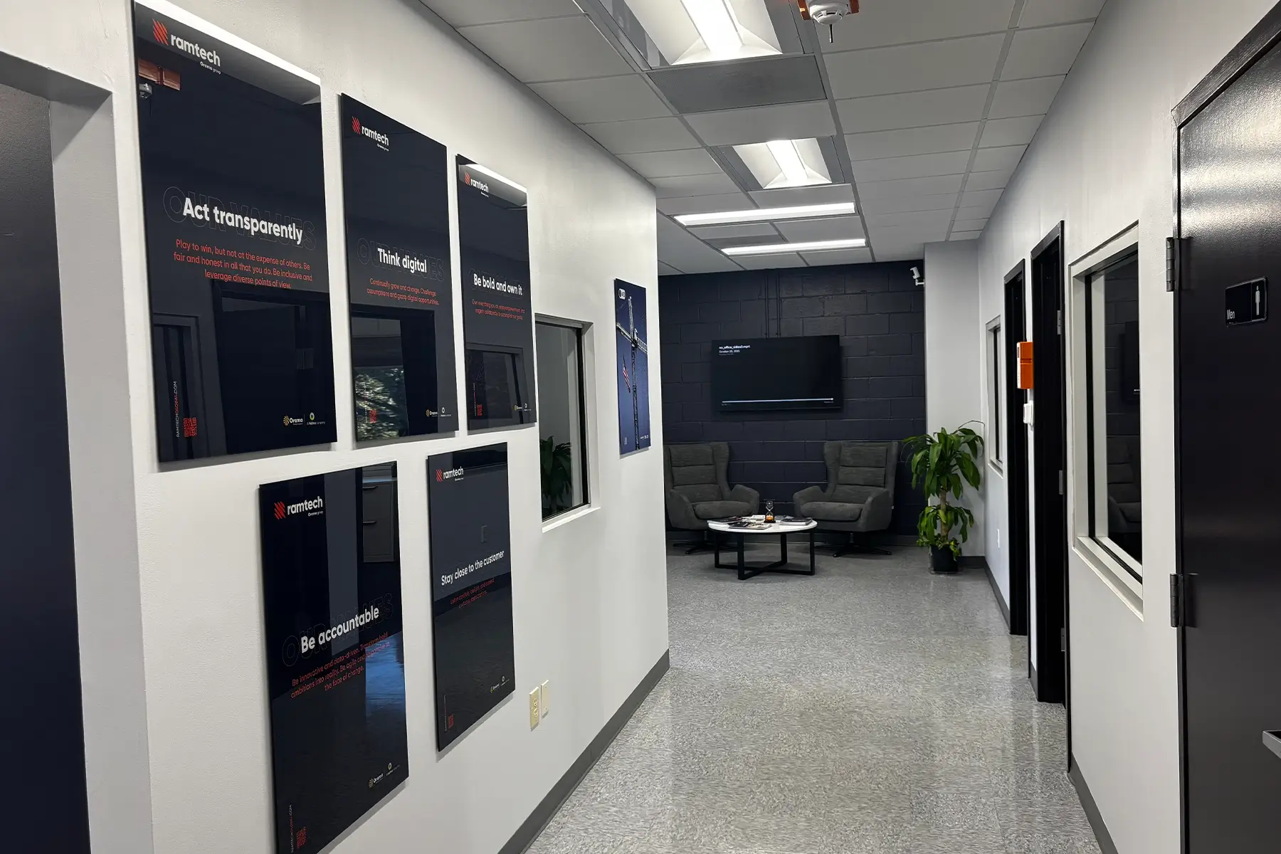 Interior view of the Ramtech Charlotte office hallway with core values posters and a comfortable seating area at the end.