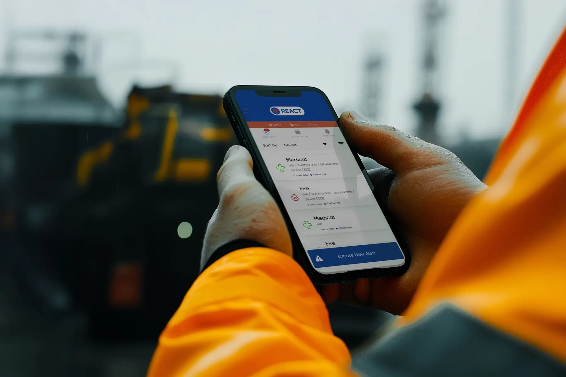 A construction worker in a high-visibility jacket holds a mobile phone displaying the REACT lone working safety app, a crucial tool for mitigating risks.
