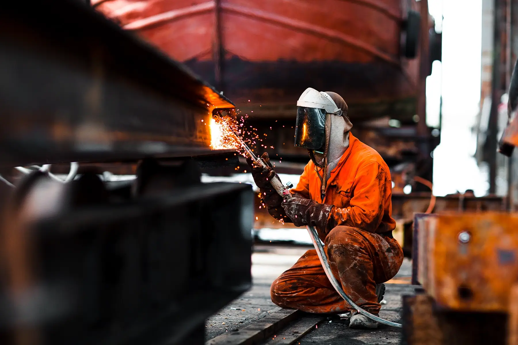 A welder working in a shipyard, a high-risk environment for fire and a perfect use case for wireless fire safety.